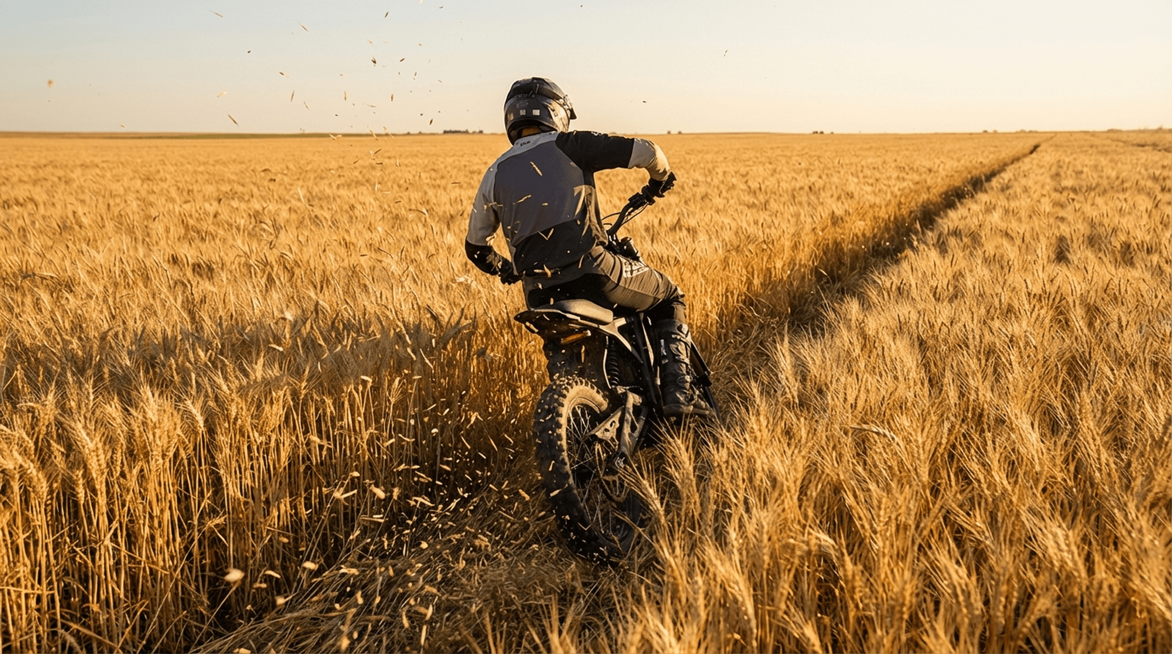 E Ride Pro SR electric dirt bike carving through a wheat field trail at golden hour